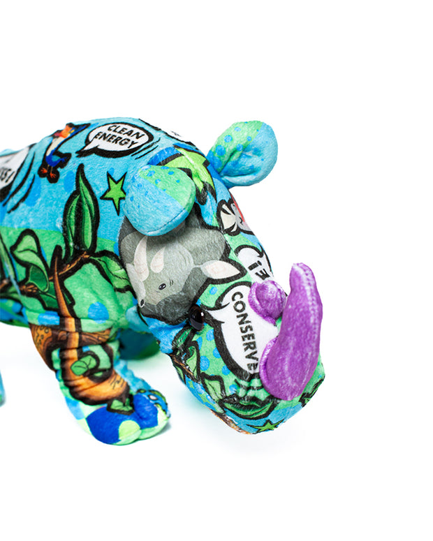 Close up of rhino plush with comic bubbles, safari animals, and has a purple tusk. 