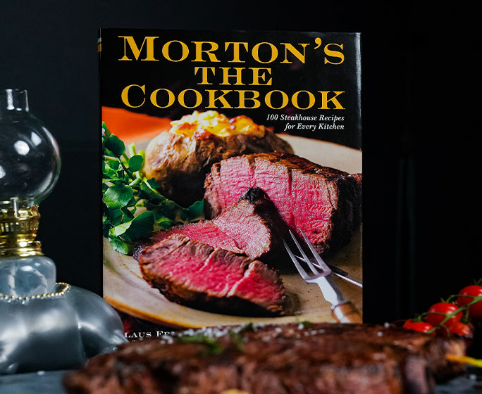 Morton's The Cookbook displayed prominently, featuring a sophisticated cover that highlights gourmet cooking.