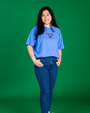 Person wearing a blue t-shirt with a logo on a green background
