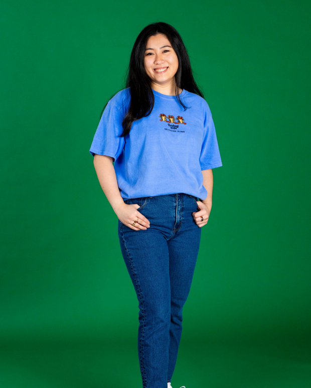 Person wearing a blue t-shirt with a logo on a green background
