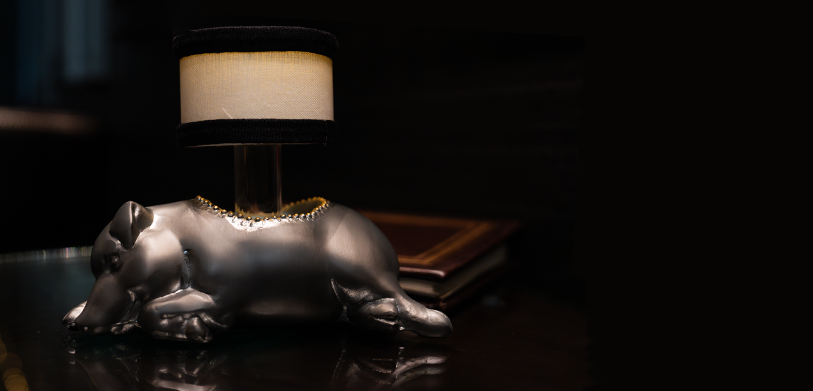 a silver pig shaped lamp elegantly placed on a table, with dim light on.