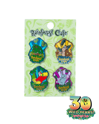 A collection of four colorful pins from Rainforest Cafe, each featuring a different animal and scene, displayed on a green decorative card. The pins include lush greenery, an animated orangutan, vibrant red macaw, green iguana  and an elephant, all celebrating ‘30 Wild Years!’ of Rainforest Cafe.