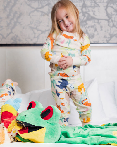 Little girl standing on bed wearing the Jungle Party toddler PJ set.