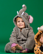 Two people in animal costumes against a green backdrop: one in a grey elephant costume with pink inner ears and white tusks, sitting cross-legged, and the other partially visible in a jaguar costume.