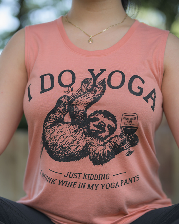 close up of a peach-colored tank top with a humorous phrase that reads, “I DO YOGA JUST KIDDING I DRINK WINE IN MY YOGA PANTS,” accompanied by an illustration of a sloth in a yoga pose holding a wine glass.