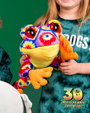 A child holding a colorful stuffed frog toy, wearing a green tie-dye shirt. Bottom right corner of image has a logo that says ‘30 WILD YEARS! Rainforest Cafe’ on it with a tree frog coming out the zero.