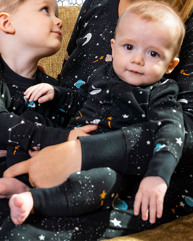 Close up of infant in mother and brother's arms while all wearing the Galaxy PJ set 