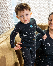 Toddler standing on couch with mother while both wear the Galaxy PJ Set.
