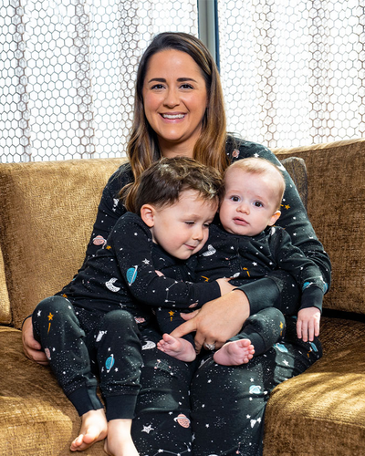 Mother sitting on couch with two young sons on her lap as all wear the Galaxy PJ set 