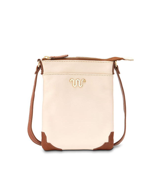 cream-colored crossbody bag with a brown bottom corner, front pocket and strap. The bag features a gold zipper and a distinctive gold emblem resembling of King Ranch logo.