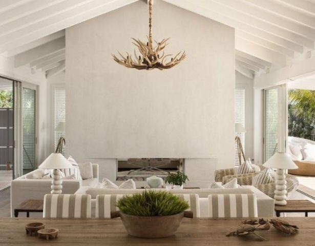 Elegant modern house with white and light brown aesthetic in living area that has antler chandelier in the center.