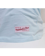 Close-up shot of the bottom hem of the same light blue short-sleeve tee with the "Mitchell & Ness" Label.