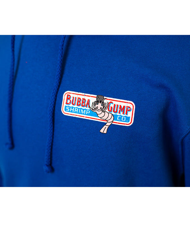 Close-up of the front of the hoodie's left chest bubba gump logo. The logo is white and rectangular, with Bubba Gump written in red with a blue shadow, pink shrimp Louis in the middle of the logo, and "shrimp cp in white font on light blue background. 