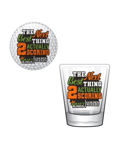 Golf ball and shot glass that have "The Next Best Thing 2 Actually Scoring" in orange and green lettering and Draft King/Golden Nugget branding.