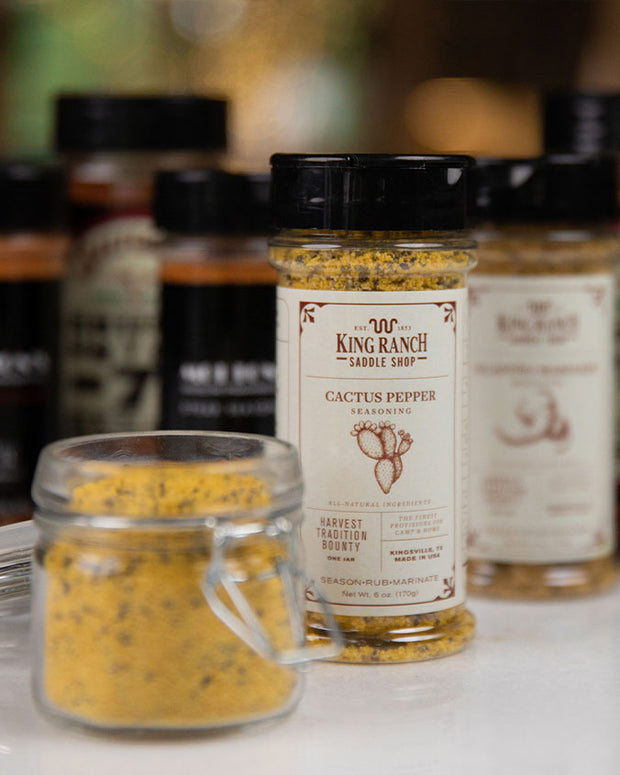 King Ranch Cactus Pepper in front of other King Ranch seasonings on a white table with small jar of seasoning next to it.