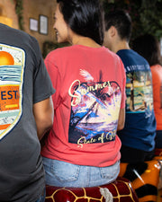 Four people sitting at a bar on top of animal print barstools. Focused in on girl wearing the Summer is a state of mind tee. On her left, a man wearing a grey tee. On her right, a man wearing a navy blue tee and at the end another girl wearing an orange shirt.