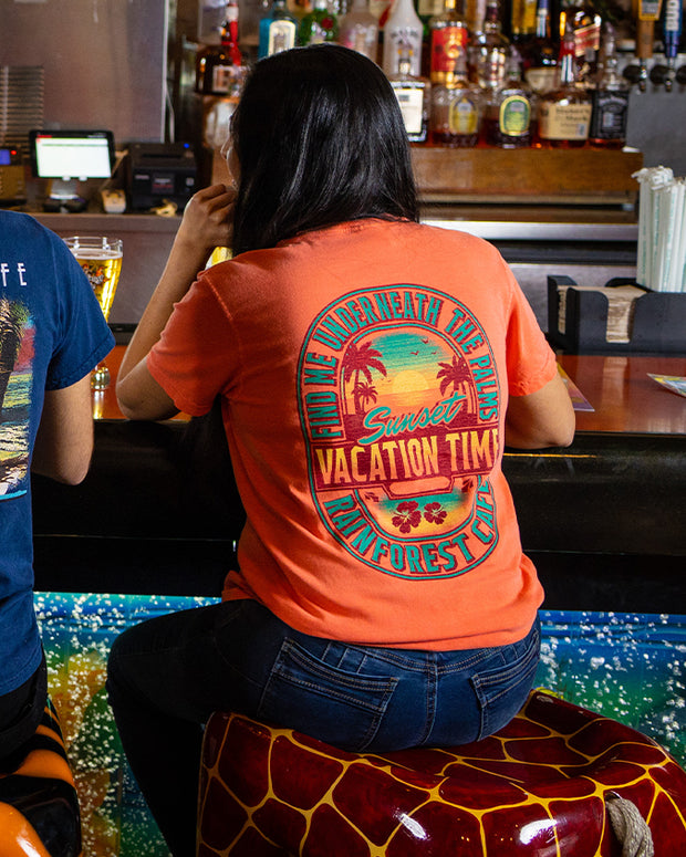 Woman sitting faciing the bar with Sunset vacation Time Tee on.