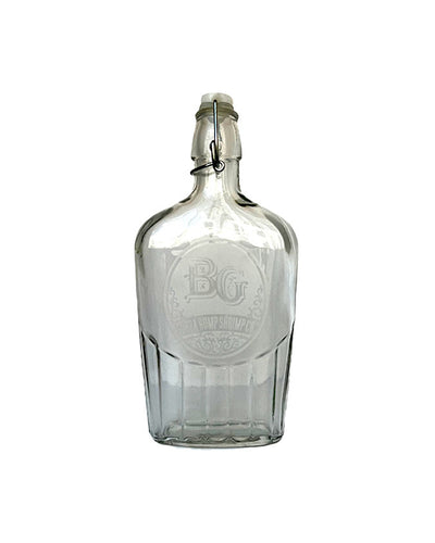 Swing top glass flask with Bubba Gump logo on the front that can hold 17 ounces placed in front of white background.