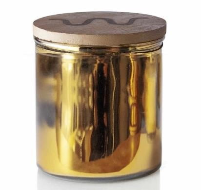 Candle with gold wrapping and King Ranch logo on lid in front of white background.