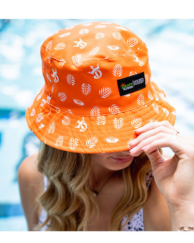 Blonde model wearing Orange Icon Bucket Hat as she sits on the poolside.